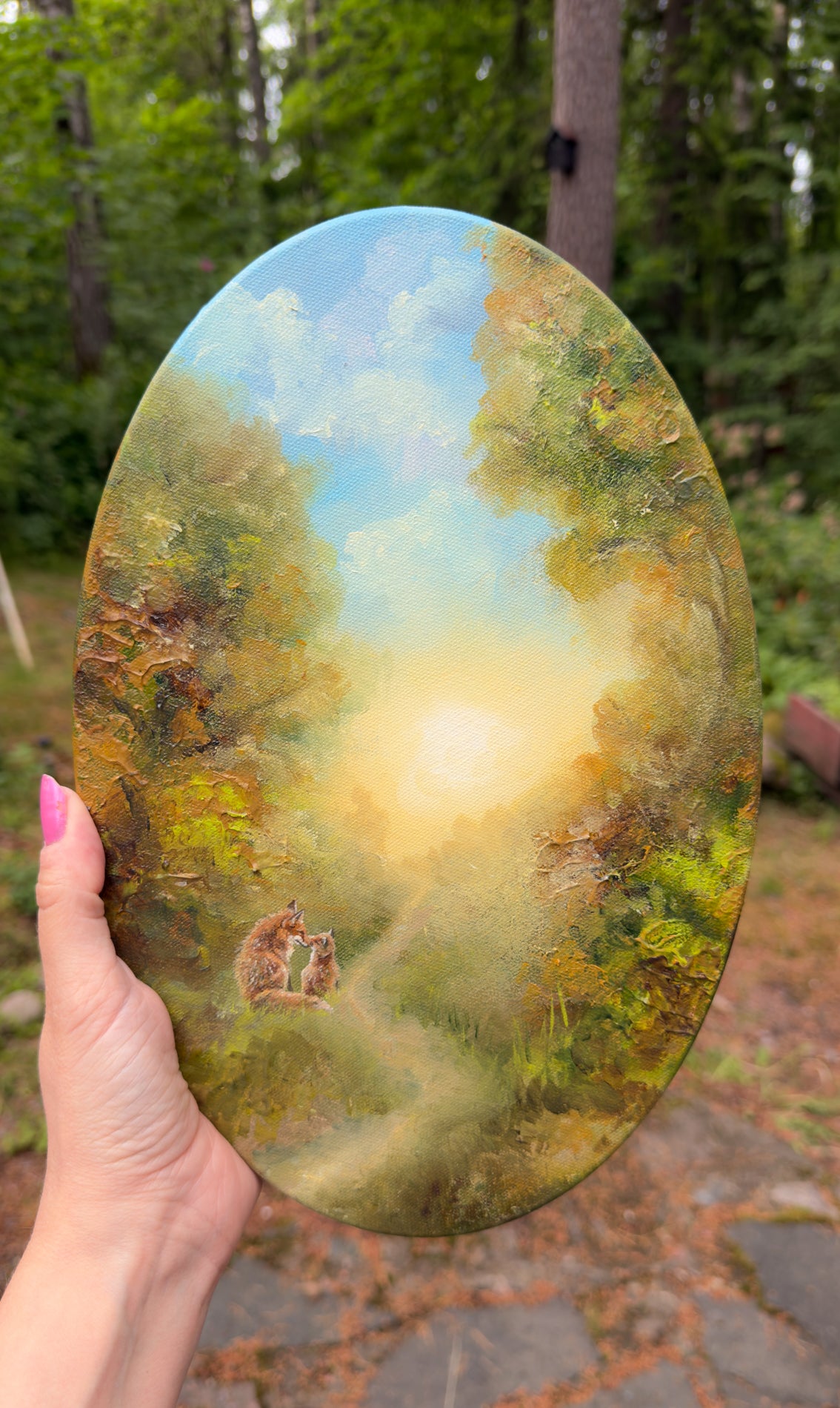 Hand holding the original oval painting outdoors to show its size.