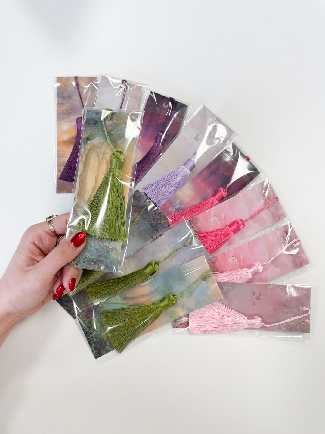 Hand holding a selection of fantasy-inspired art bookmarks featuring different original artworks.